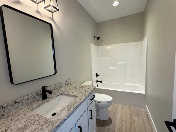 a bathroom with a granite countertop sink toilet and shower