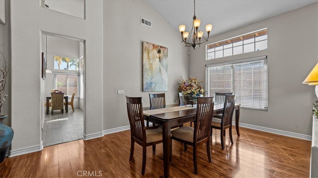1671 Dominguez Ranch Road Corona, CA 92878 - Photo 14 of 42 This formal dining space features vaulted ceilings, large windows, and warm wood flooring, creating an inviting setting for gatherings and everyday meals.