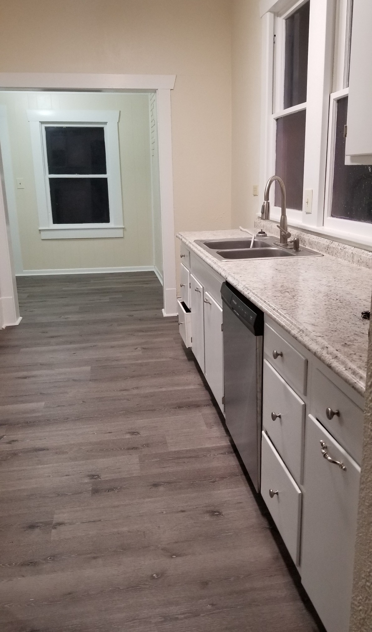 1034 Magnolia Street Lockhart, TX 78644 - Photo 12 of 12 Kitchen with light countertops, dark wood finished floors, stainless steel dishwasher, and white cabinets