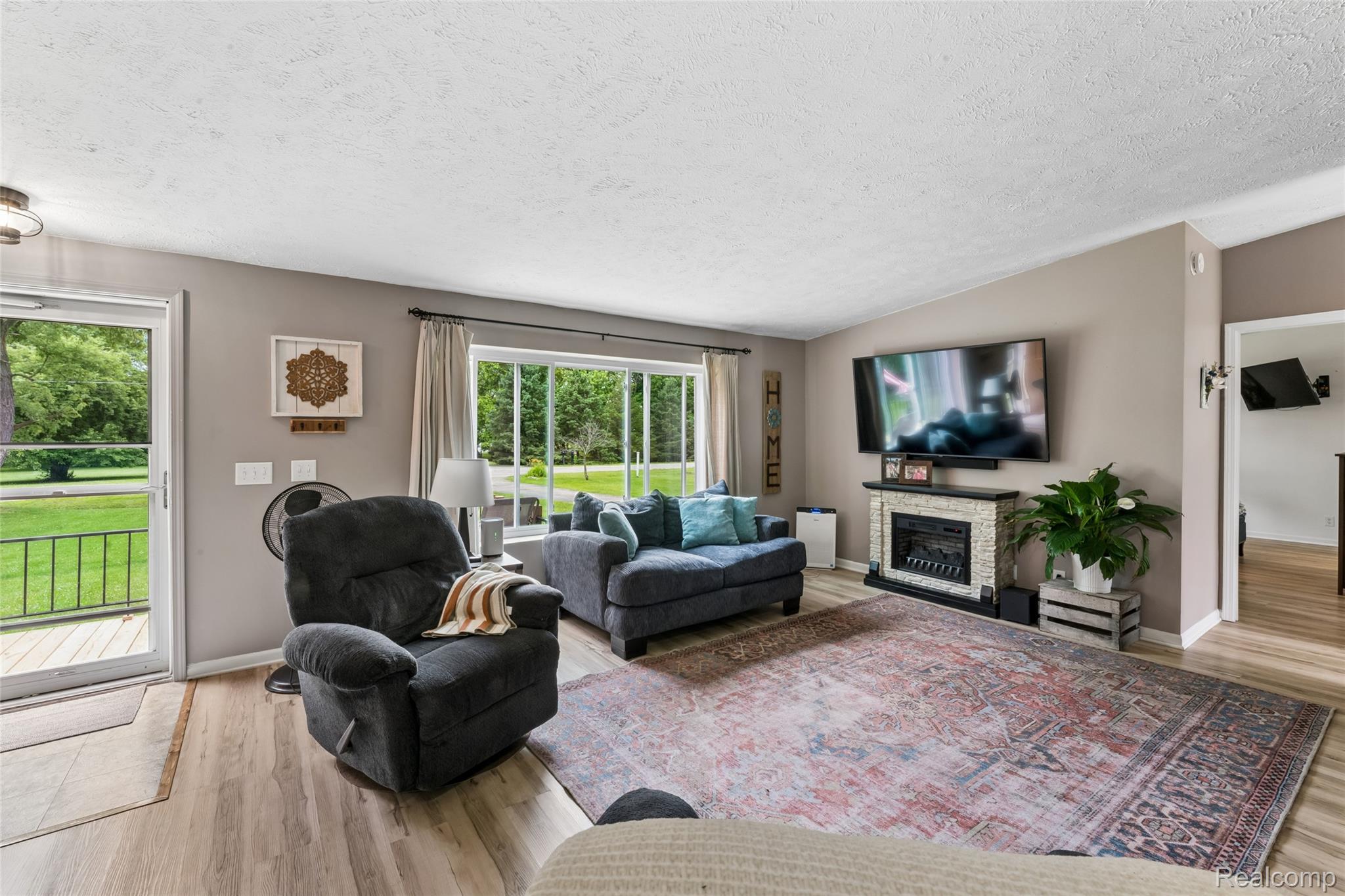 1336 West Hurd Road Clio, MI 48420 - Photo 17 of 43 Living area featuring wood-finish flooring, a built-in fireplace with a tiled surround, and large windows providing natural light