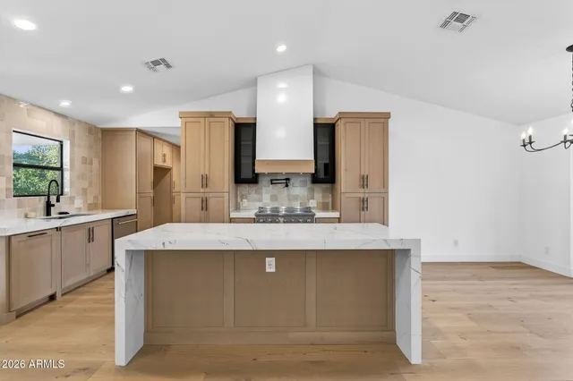 a large kitchen with stainless steel appliances kitchen island a large counter top and wooden floors
