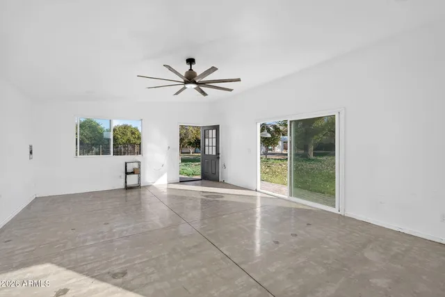 a view of an empty room with a window and kitchen view