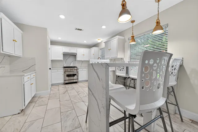 a kitchen with stainless steel appliances granite countertop a refrigerator a stove a sink dishwasher and white cabinets with wooden floor