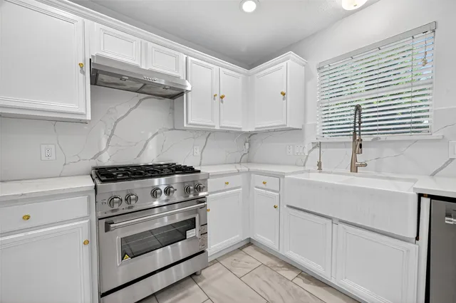 a kitchen with white cabinets and appliances