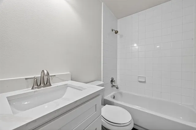 a bathroom with a granite countertop bathtub shower sink vanity mirror and toilet