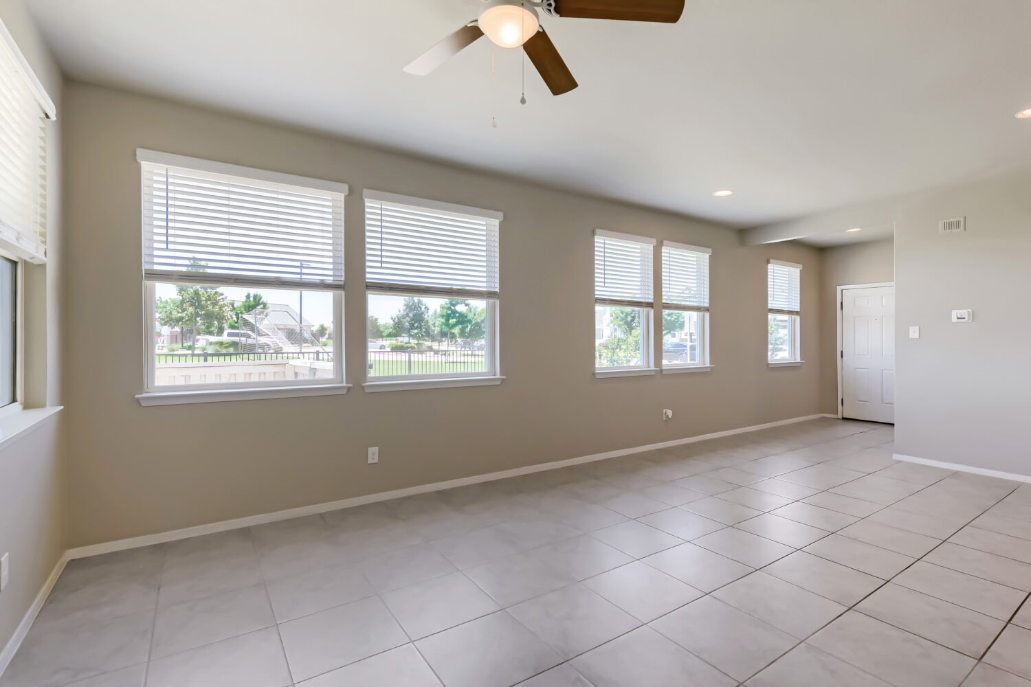 1310 Goforth Road Kyle, TX 78640 - Photo 7 of 24 Spacious living area featuring large windows with blinds, recessed lighting, a ceiling fan, and light-toned tile flooring