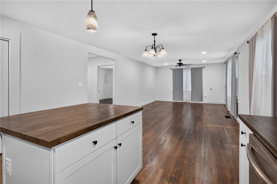115 Pelfrey Street Seneca, SC 29672 - Photo 10 of 46 Rich hardwood flooring stretches across an open-concept living space, illuminated by modern fixtures and natural light.