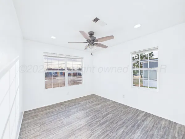 a view of an empty room with a window and wooden floor