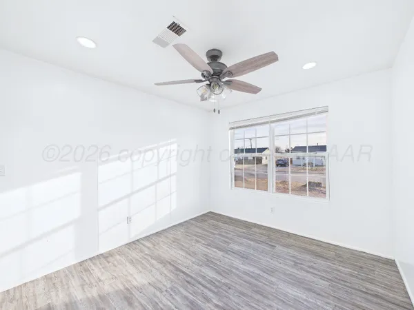 a view of empty room with wooden floor and fan
