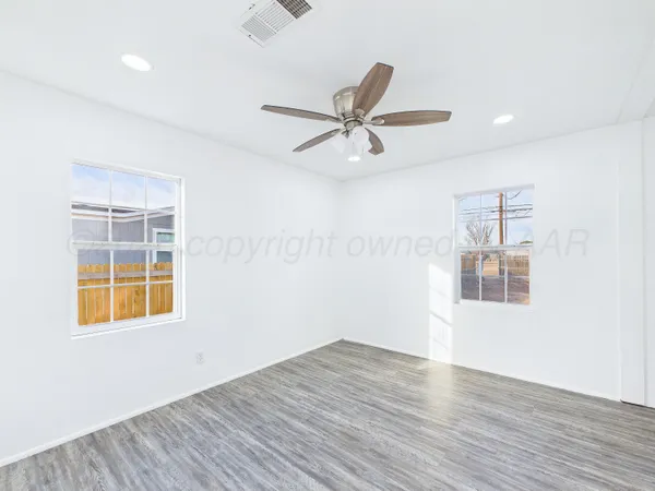 a view of empty room with wooden floor and fan