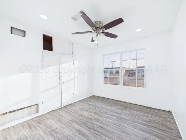 a view of empty room with wooden floor and fan