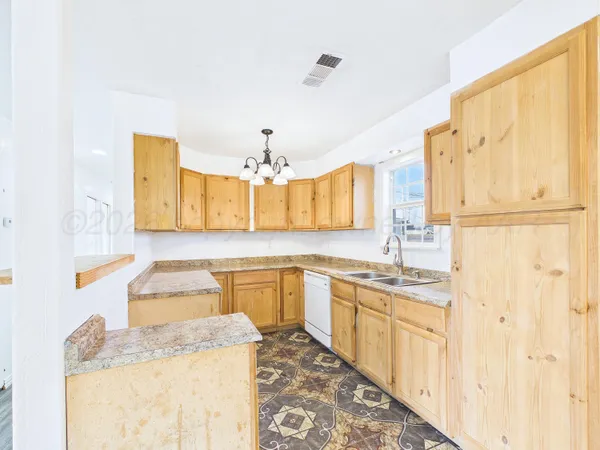 a kitchen with granite countertop a sink a counter space and cabinets