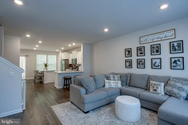 a living room with furniture kitchen view and a wooden floor