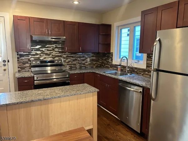 a kitchen with granite countertop a refrigerator and a sink