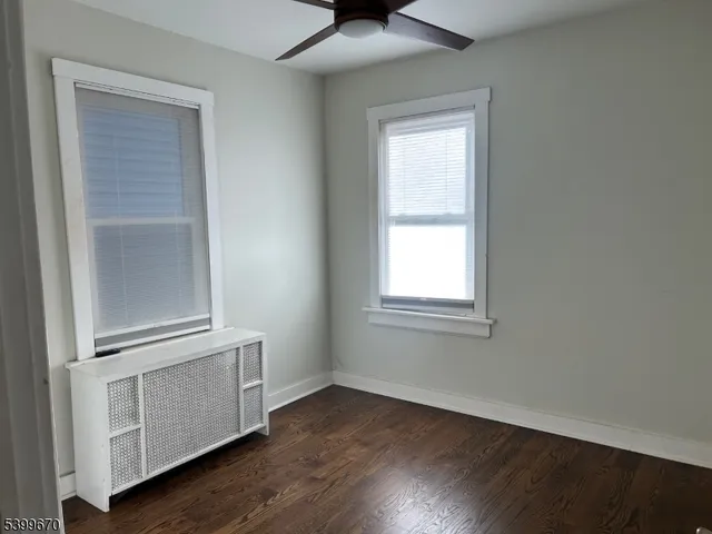 an empty room with wooden floor cabinet and windows