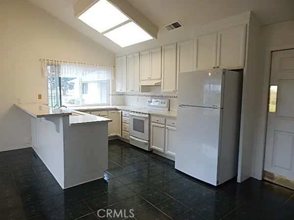 a kitchen with a sink a refrigerator a window and cabinets