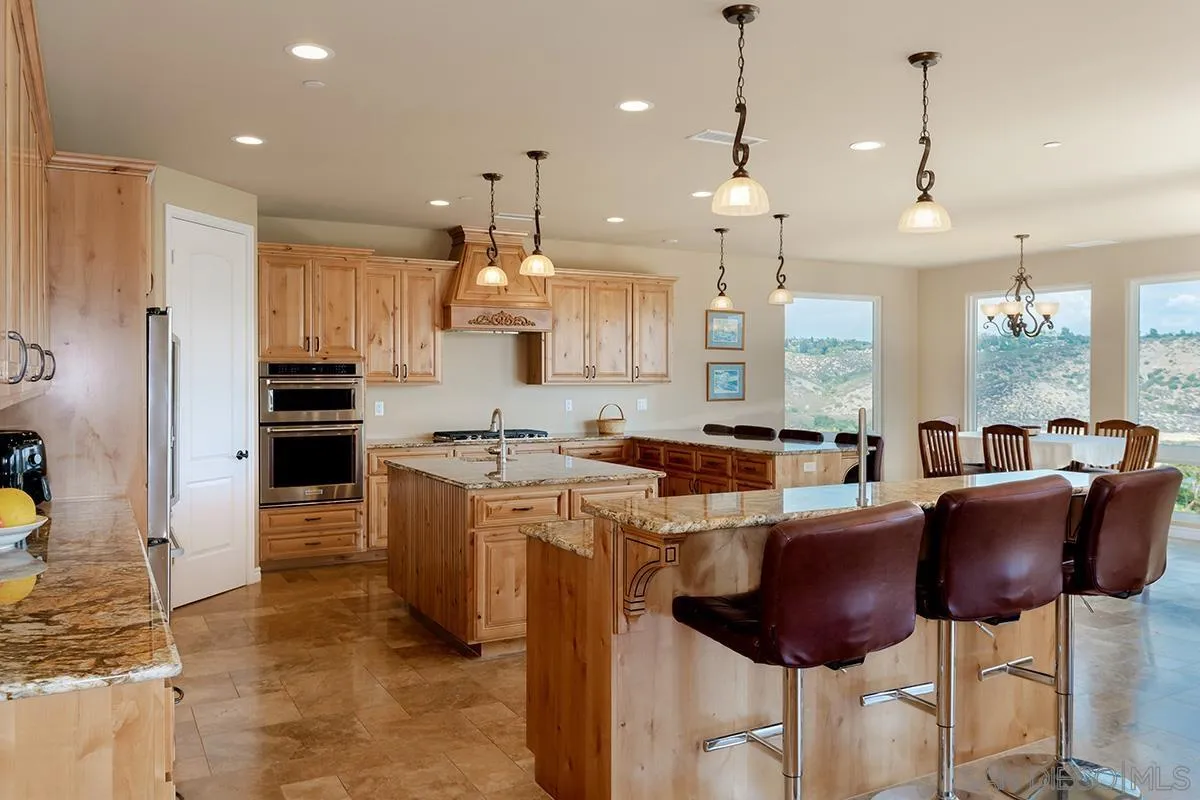 19840 7th Place Escondido, CA 92029 - Photo 16 of 49 a kitchen with stainless steel appliances granite countertop a stove a refrigerator a oven a sink with a dining table and chairs