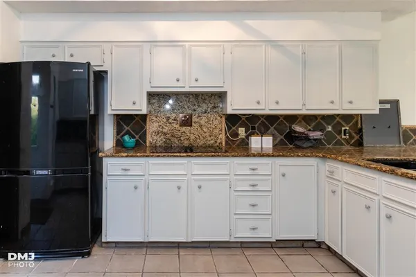a kitchen with white cabinets and refrigerator