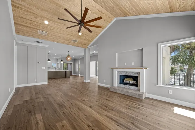 a view of an empty room with a window and wooden floor