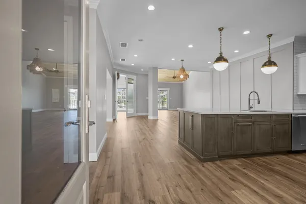 a large kitchen with stainless steel appliances a large counter top a sink a refrigerator and a wooden floors