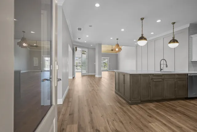 a large kitchen with stainless steel appliances a large counter top a sink a refrigerator and a wooden floors