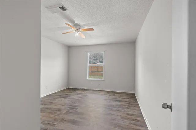 an empty room with a window and ceiling fan