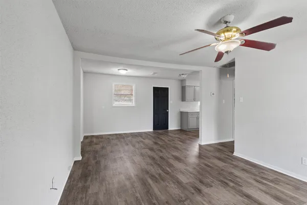 a view of an empty room with window and wooden floor