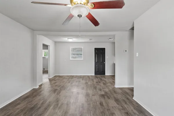 a view of an empty room with window and wooden floor