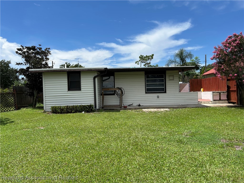 11 Mockingbird Road Lake Placid, FL 33852 - Photo 31 of 41 THIS IS A VIEW OF THE BACK YARD AND THE BACK OF THE HOME WITH A CONCRETE WALKWAY FOR SITTING WITH A GOOD BOOK