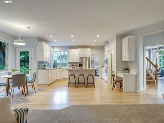 a living room with furniture a dining table and kitchen view with wooden floor