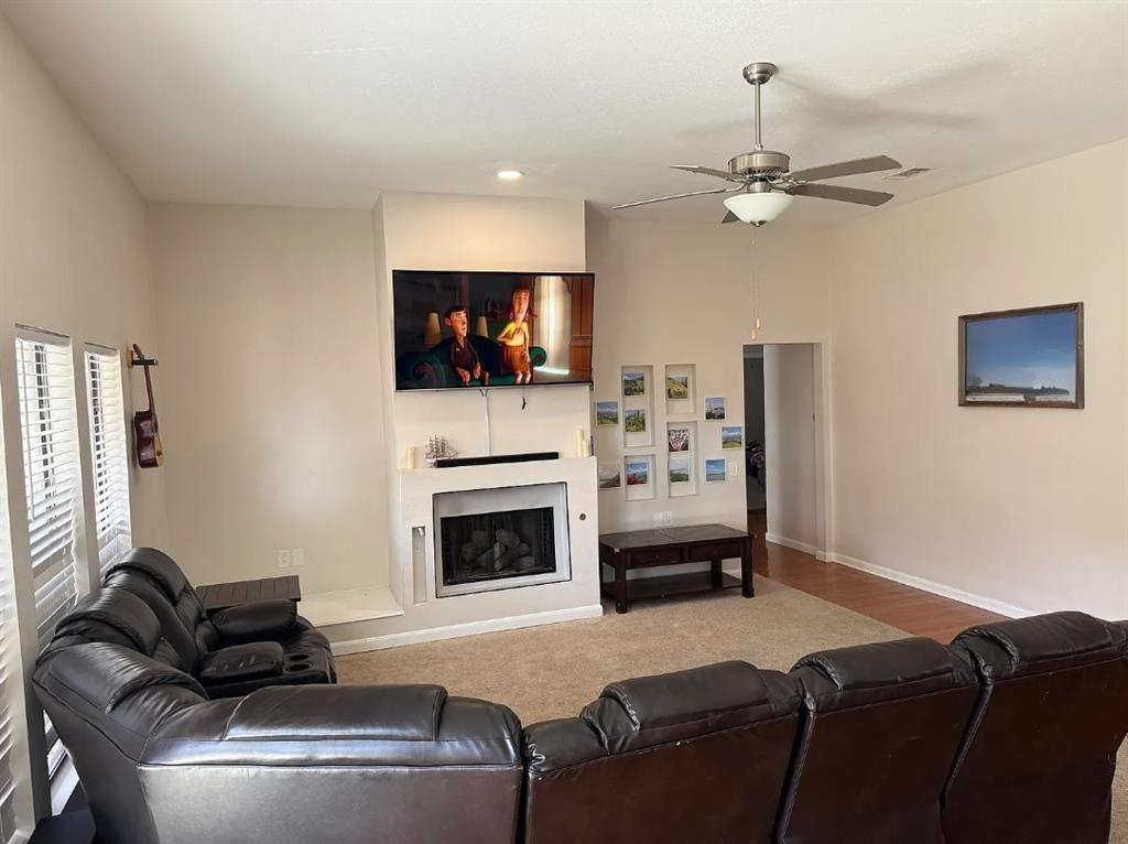 6505 Mc Cormick Ranch Court Plano, TX 75023 - Photo 2 of 21 Living area featuring a carpeted floor, built-in fireplace, and a ceiling fan with integrated lighting