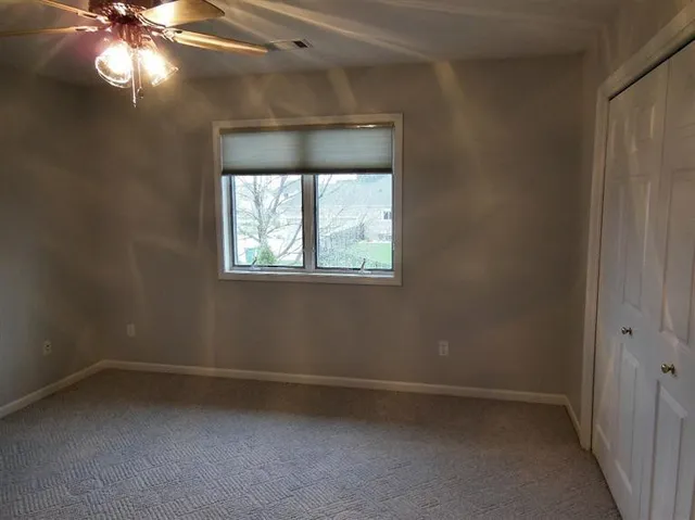 an empty room with windows and fan