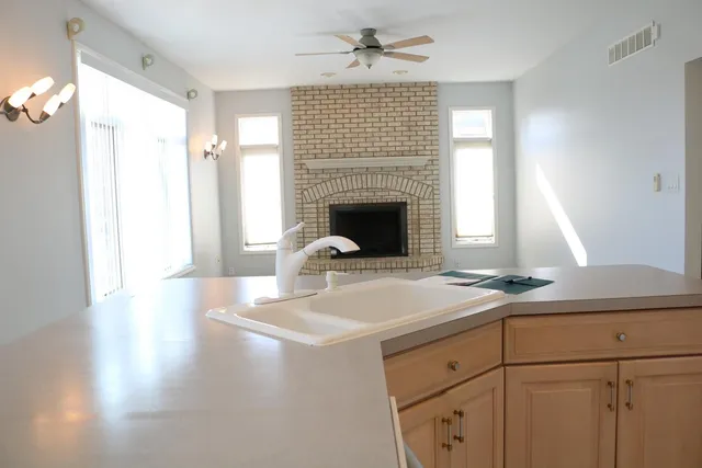 a living room with kitchen island a fireplace wooden floor and a window