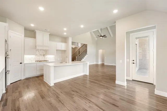 a large white kitchen with white cabinets and wooden floor