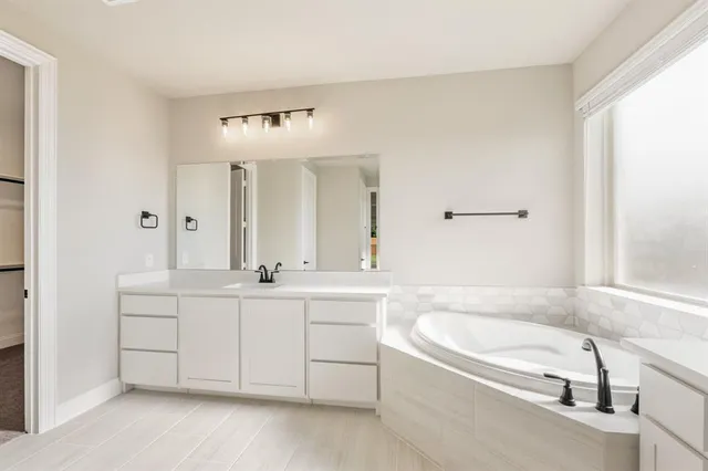a spacious bathroom with a bathtub a double vanity sink and mirror