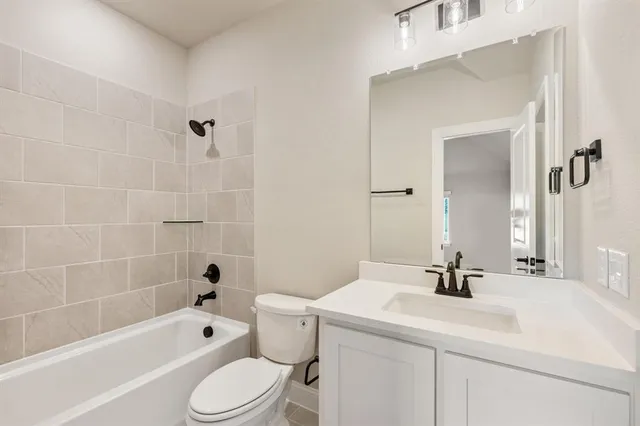 a bathroom with a bathtub shower sink vanity mirror and toilet