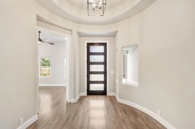 an empty room with wooden floor cabinet and windows