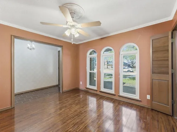 an empty room with wooden floor fan and windows