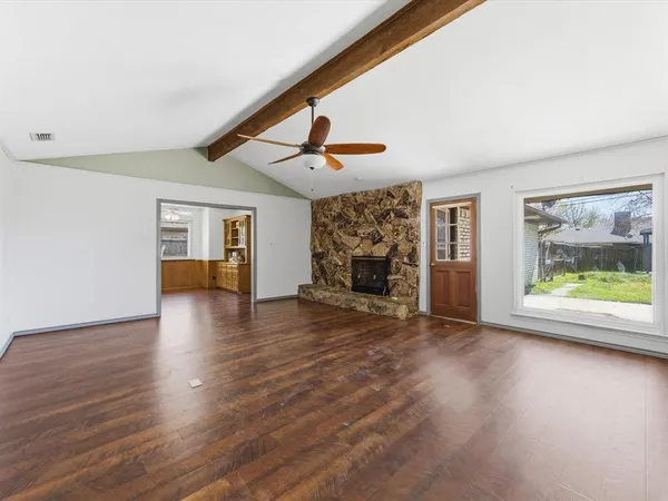 a view of empty room with wooden floor and fan