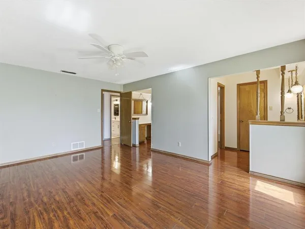 a view of an empty room with window and wooden floor