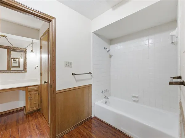 a bathroom with a bathtub a toilet a sink and wooden floor