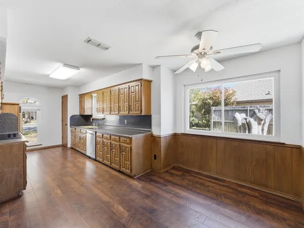 a open kitchen with stainless steel appliances granite countertop a refrigerator a stove a sink dishwasher and white cabinets with wooden floor