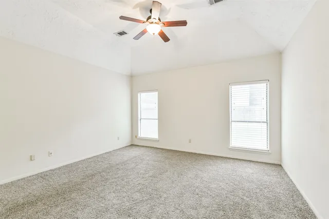 an empty room with windows and fan