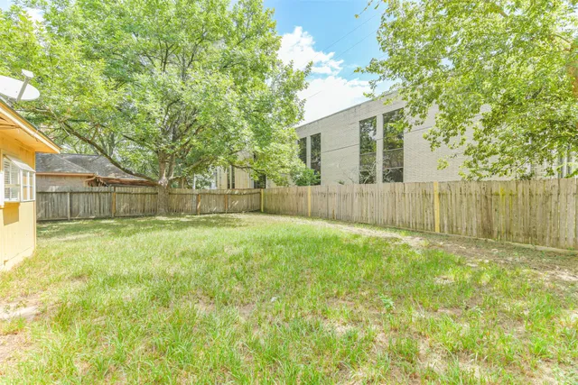 a backyard of a house with a fountain and a large tree