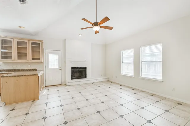a view of a livingroom with a fireplace a ceiling fan and windows