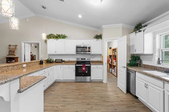 a kitchen with granite countertop a stove top oven a sink dishwasher and a refrigerator with wooden floor