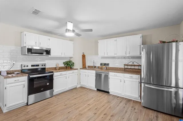 a kitchen with cabinets stainless steel appliances and a window