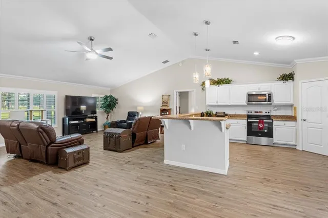 a view of kitchen with kitchen island stainless steel appliances refrigerator stove and couches with wooden floor