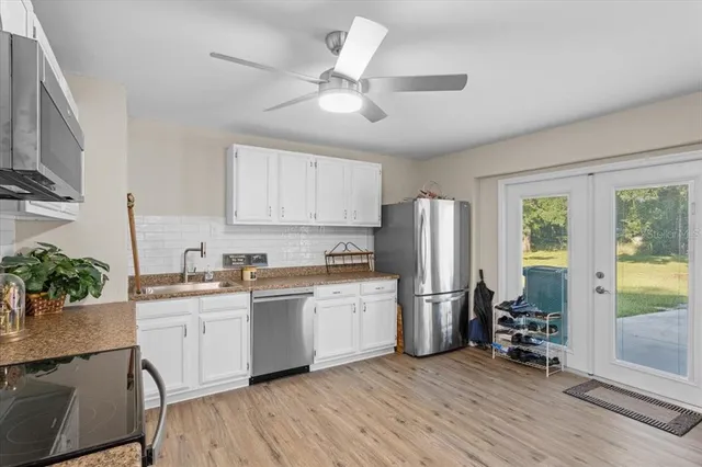 a kitchen with stainless steel appliances granite countertop a refrigerator a sink a stove and white cabinets