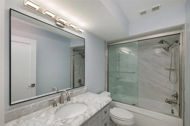 a bathroom with a granite countertop sink a toilet and shower